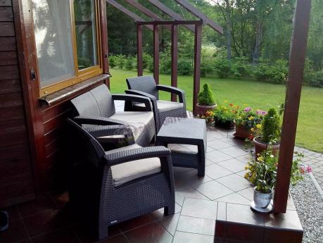 Brązowy zestaw mebli ogrodowych Corfu Curver na rozkwieconym tarasie