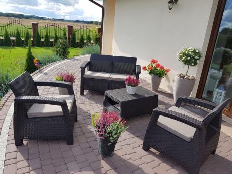 Brązowy zestaw na taras Allibert Keter Corfu Set w otoczeniu kwiatów