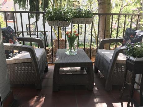 Meble Corfu Weekend na niedużym balkonie ozdobione dużą ilością kwiatów