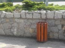 Kosz na śmieci okrągły na tle kamienia w parku