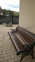 Ozdobna ławka ogrodowa drewniana ustawiona na chodniku