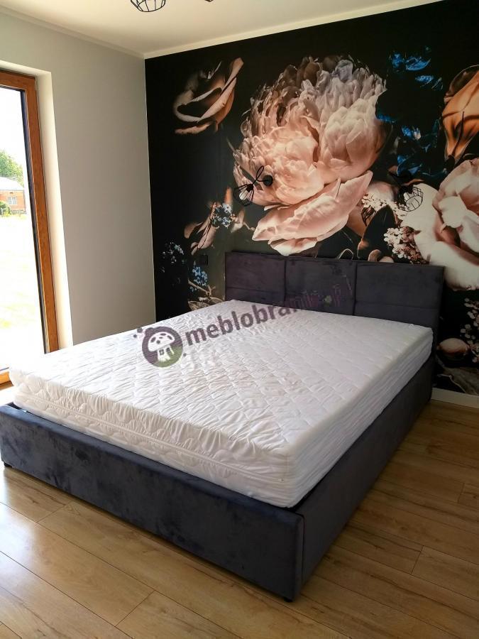 ciemnoszare welurowe łóżko dla 2 osób w sypialni z tapetą