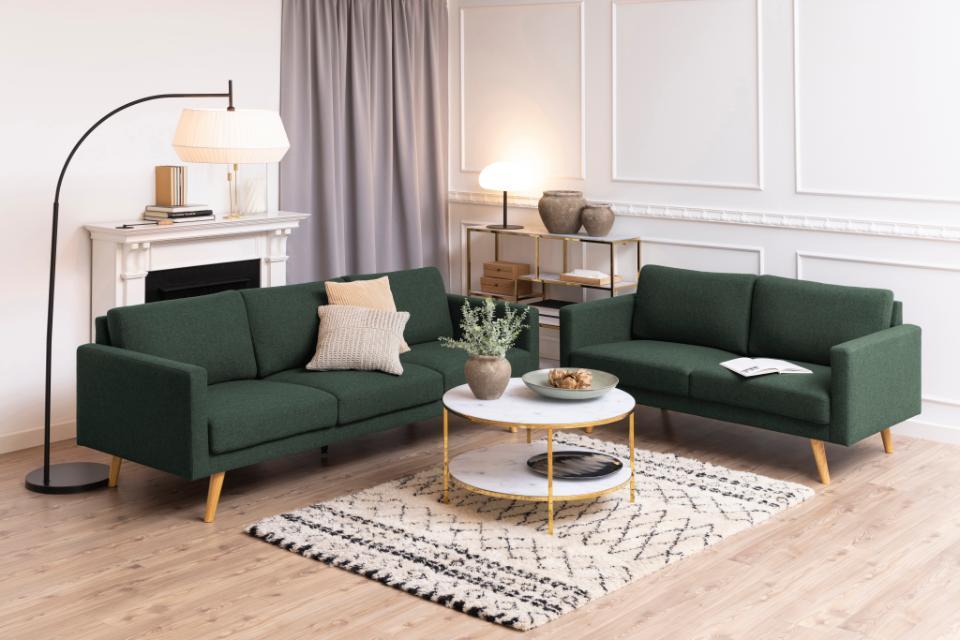 ciemnozielona sofa na nożkach w salonie